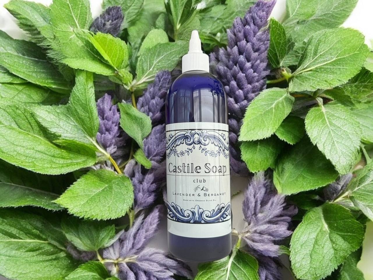 Organic Castile Liquid Soap bottle with peppermint and juniper surrounded by fresh leaves and lavender flowers, showcasing natural ingredients.